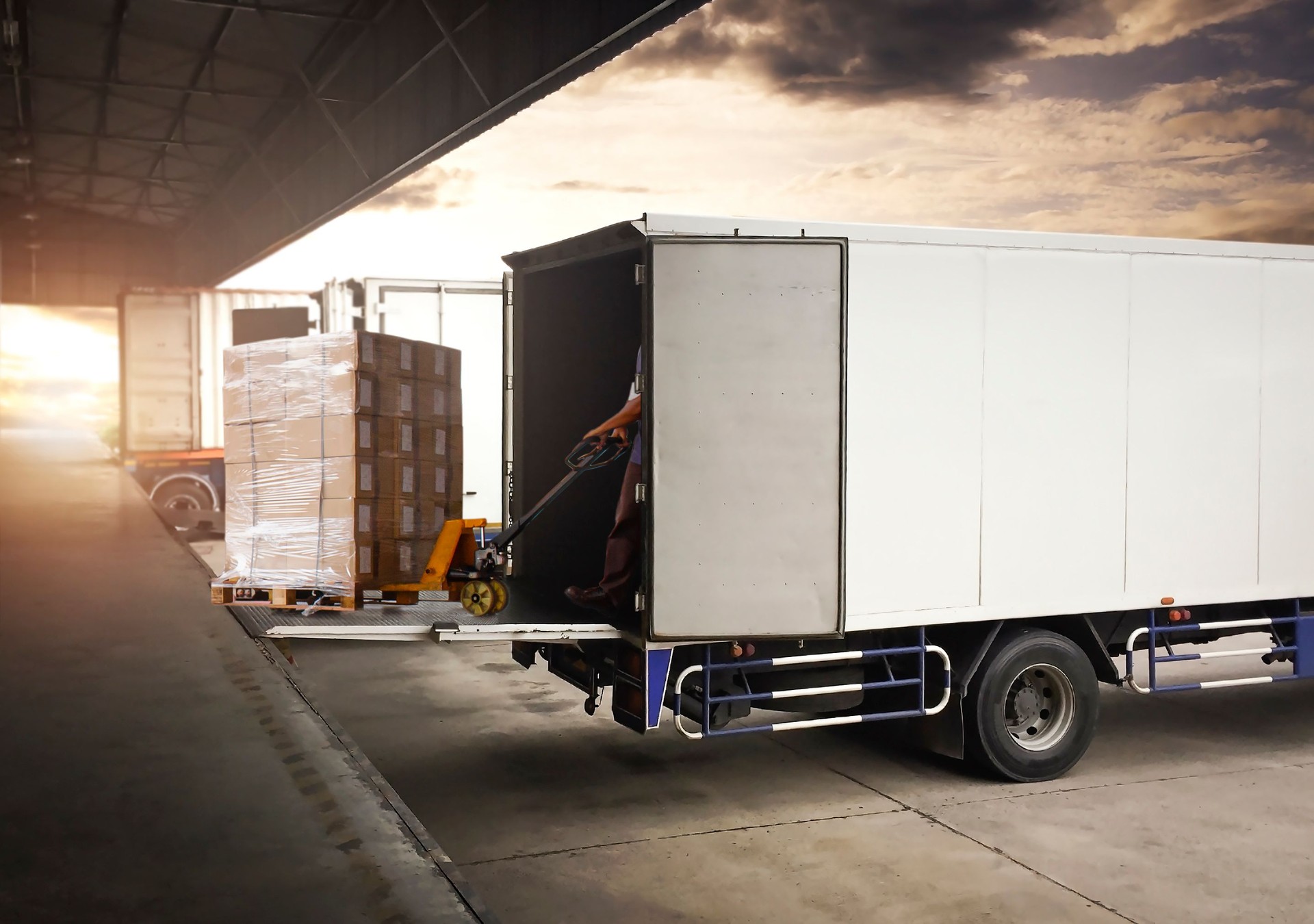 Workers Using Hand Pallet Jack Unloading Packaging Boxes into Cargo Container. Delivery Trucks Shipment. Trucks Loading at Dock Warehouse. Supply Chain. Warehouse Shipping Transport and Logistics.