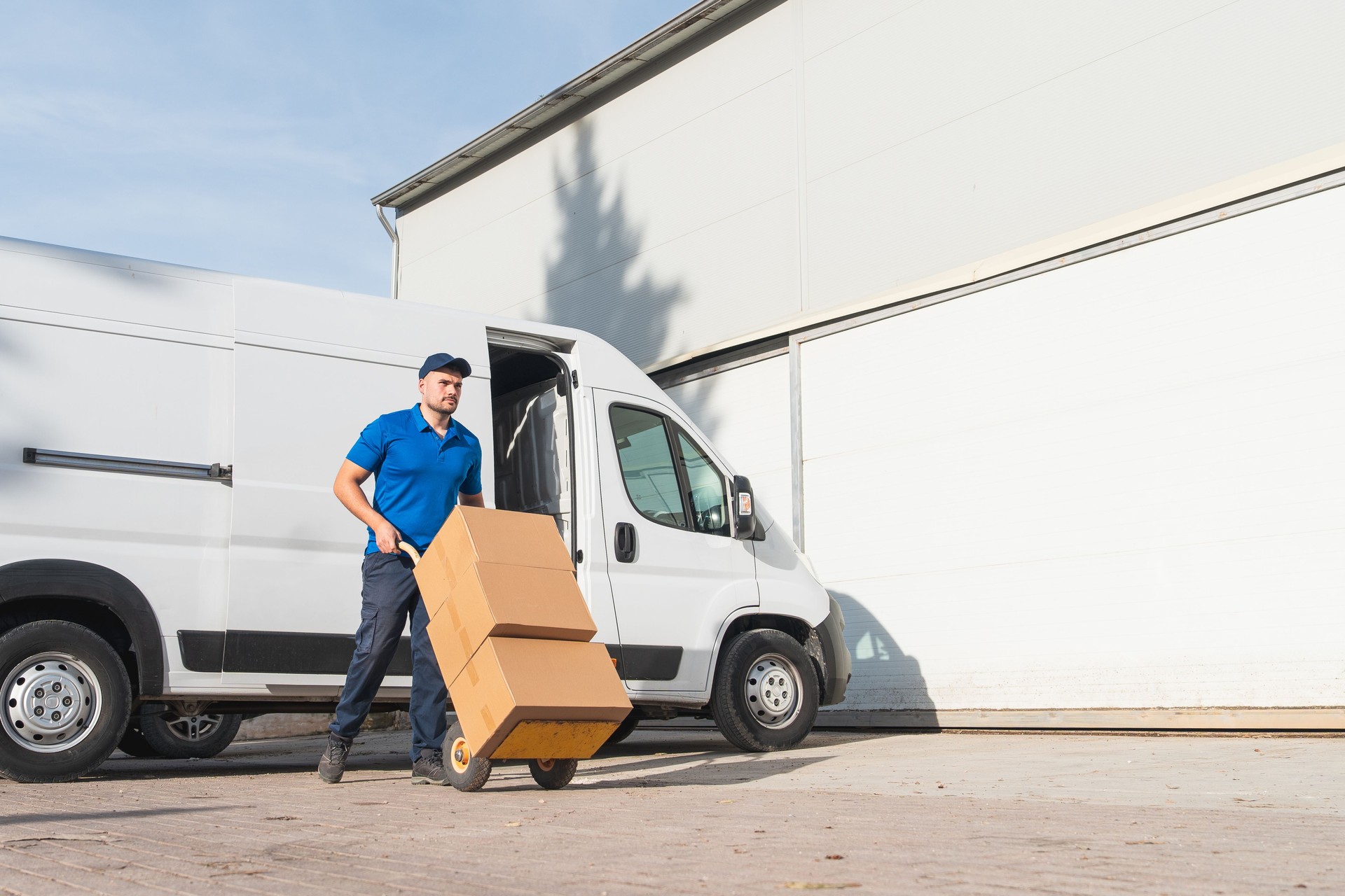 Courier Pulling Hand Truck with Boxes from Delivery Van